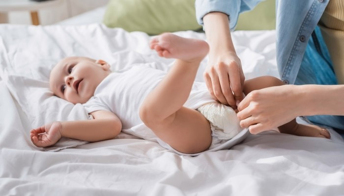 Should I wake a sleeping baby to change a poopy diaper?